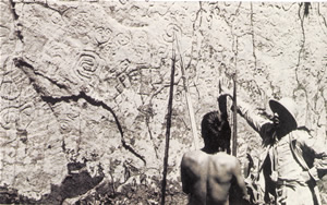 Esta foto de los años 1940 muestran Fray Vicente de Cenitagoya, descubridor del sitio (1921), al pie de la pared principal de Pusharo. Varias figuras visibles sobre esta foto están hoy bajo el nivel actual del suelo. (Foto: Vicente de Cenitagoya, 1947)